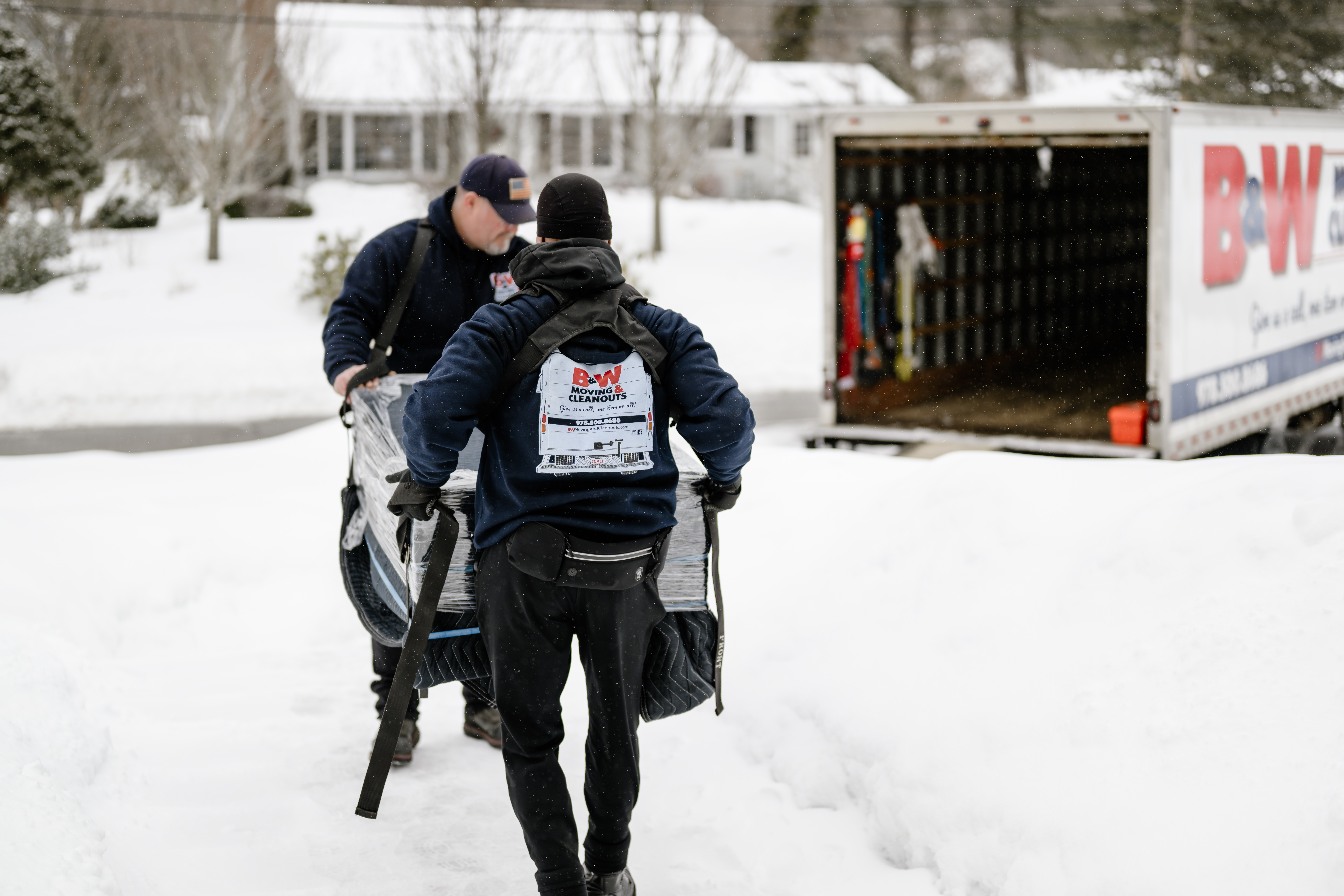 B&W Crew Carrying Furniture Through Snow